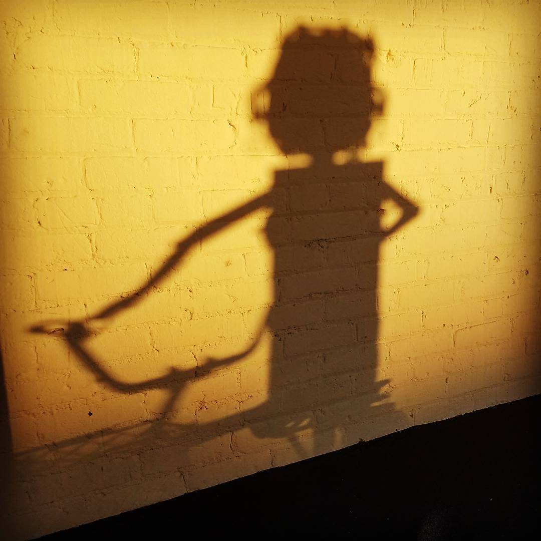 Shadow of a biker on a yellow wall.